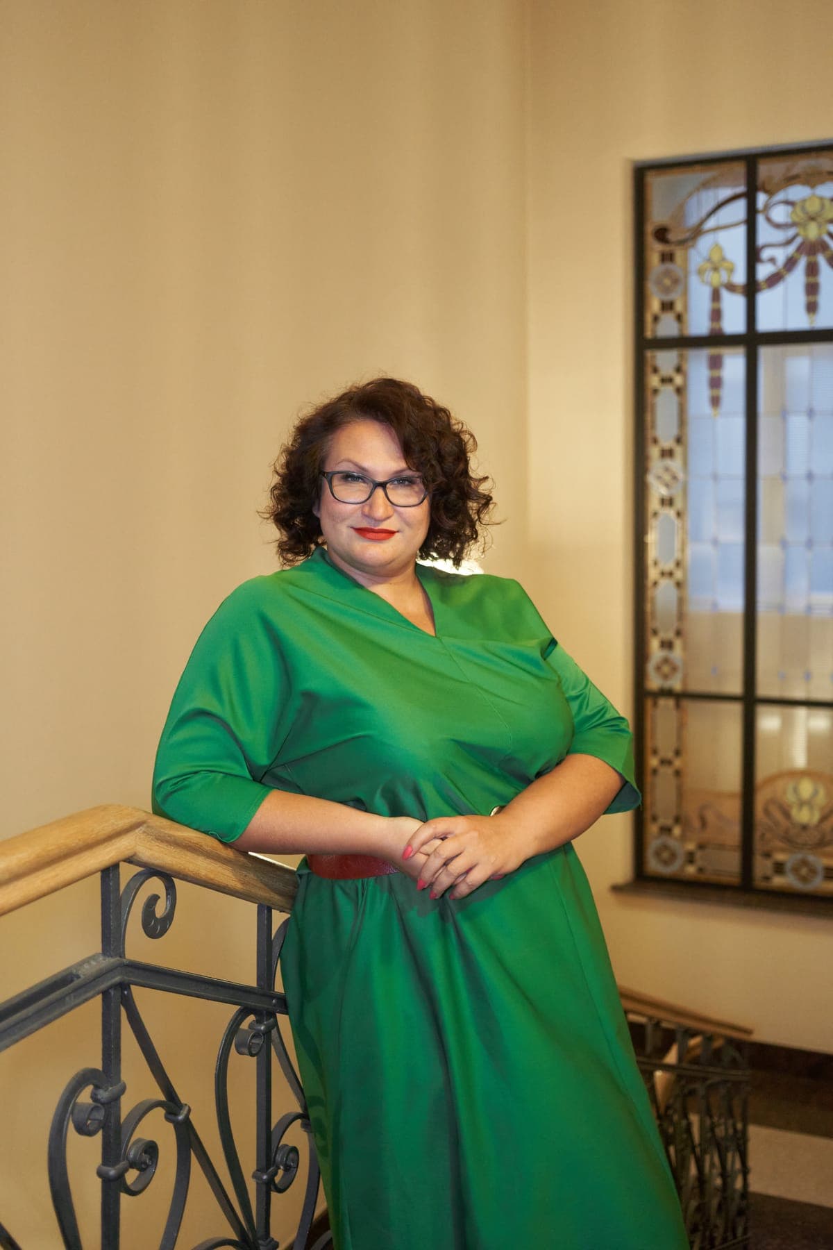 Марина Шолухина, ведущая интенсива, в зелёном платье на фоне витража